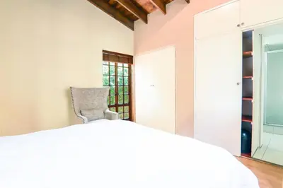 a bedroom with a white bed and a chair at Private room with en-suite bathroom in Pretoria