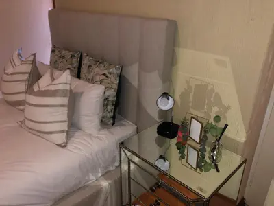 a small bed with white pillows and a glass table at Private room with en-suite bathroom in Pretoria