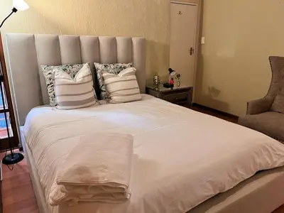 a large white bed with pillows and a chair at Private room with en-suite bathroom in Pretoria
