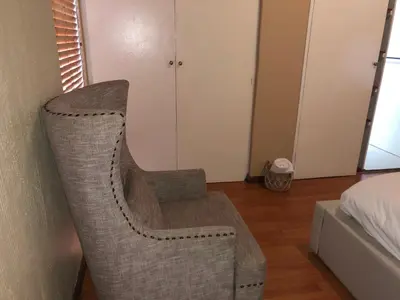 a rattan chair in a room with a bed at Private room with en-suite bathroom in Pretoria
