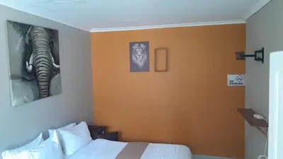 a bedroom with an elephant picture on the wall at Emasimini Cottages in Midrand
