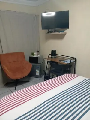 a bedroom with a bed and a chair and a television at Comfort Place 4 in Pretoria
