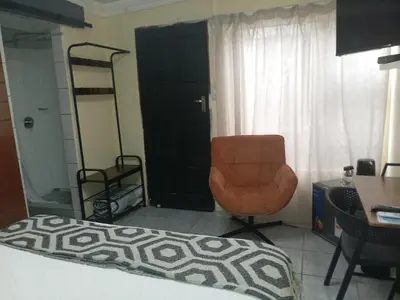 a bedroom with a bed and a chair and a table at Comfort Place 4 in Pretoria