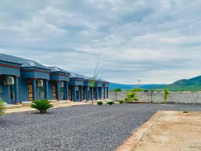 a row of blue buildings with mountains in the background at Morning Star Guest House & Lodge in Burgersfort