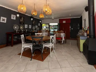 a dining room with a wooden table and chairs at Woodpecker's Guest House in Hazyview