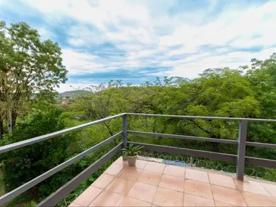 a balcony with a view of the forest at Woodpecker's Guest House in Hazyview