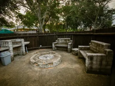 a group of benches and a fire pit in a backyard at Weavers Nest Guesthouse in Modimolle