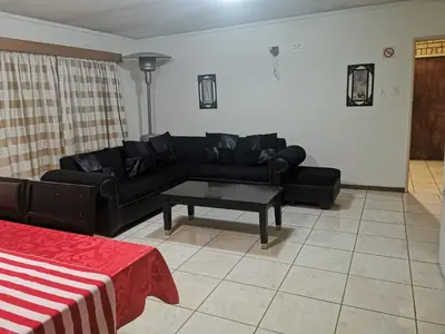 a living room with a black couch and a table at Charming Tshwane BB with Secure Entrance Central AC in Pretoria