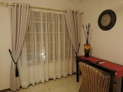 a room with a window with a table and a clock at Charming Tshwane BB with Secure Entrance Central AC in Pretoria
