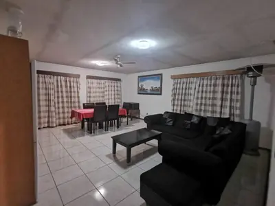 a living room with a black couch and a table at Charming Tshwane BB with Secure Entrance Central AC in Pretoria