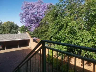 a balcony with a fence and a tree with purple flowers at Charming Tshwane BB with Secure Entrance Central AC in Pretoria
