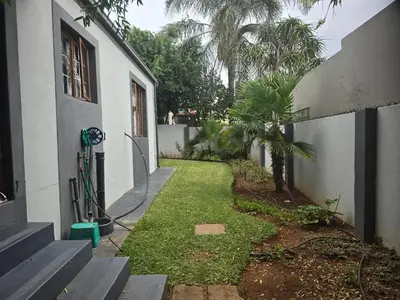 a yard next to a house with a palm tree at The Chardonay Inn in Centurion
