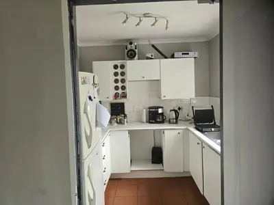 a small kitchen with white cabinets and a refrigerator at The Chardonay Inn in Centurion
