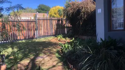 a backyard with a fence and a yard with plants at The Chardonay Inn in Centurion