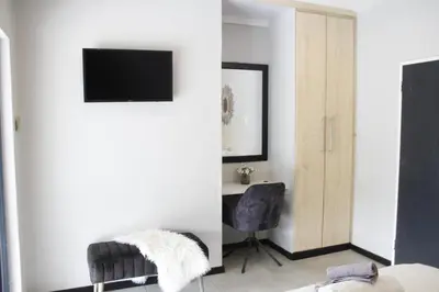 a living room with a television and a chair at Aeon Guest House & Spa in Pretoria