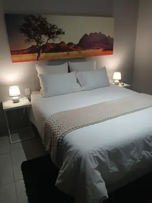a bedroom with a large white bed with two lamps at Aeon Guest House & Spa in Pretoria