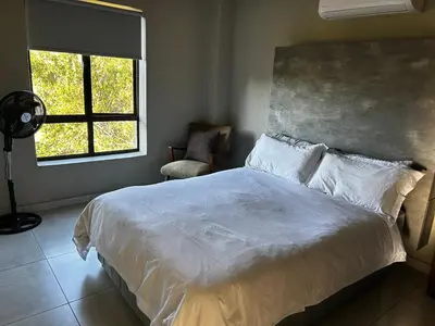 a bedroom with a white bed and a window at Kingfisher's Song in Nelspruit