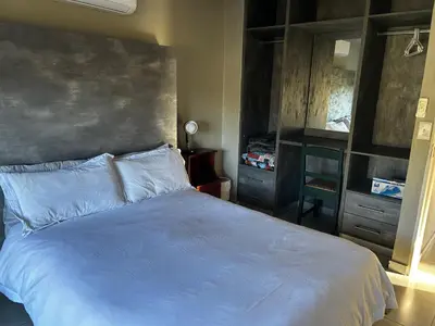 a bedroom with a large white bed and a dresser at Kingfisher's Song in Nelspruit