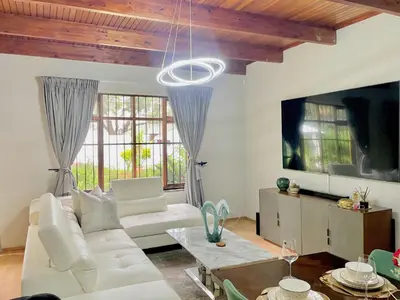 a living room with a white couch and a tv at Avenue luxury home in Pretoria