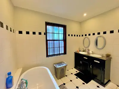 a bathroom with a bath tub and two sinks at Avenue luxury home in Pretoria
