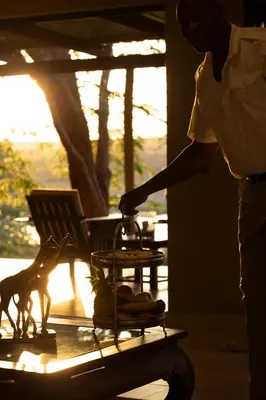 a person standing next to a table with a lantern at Elephant Walk Tented Camp in Komatipoort