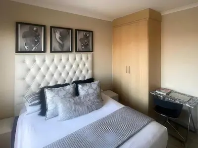 a bedroom with a white bed with a large headboard at Capricon Village 3 Bedroom Villa in Centurion