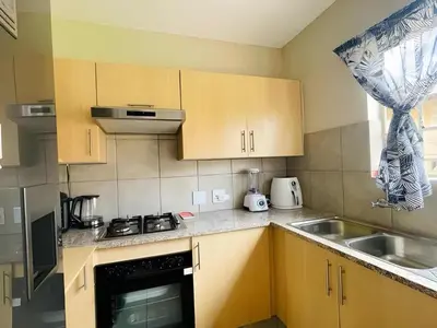 a kitchen with wooden cabinets and a stove and a sink at Capricon Village 3 Bedroom Villa in Centurion