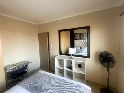 a bedroom with a bed and a mirror and a fan at Capricon Village 3 Bedroom Villa in Centurion