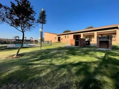 a building with a tree in front of a yard at Capricon Village 3 Bedroom Villa in Centurion