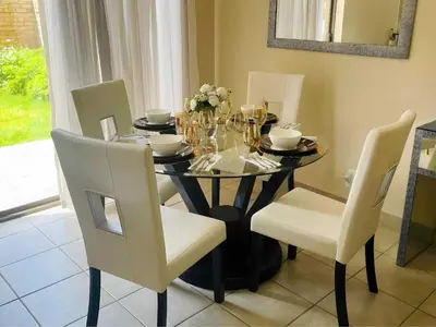 a dining room table with chairs and wine glasses on it at Capricon Village 3 Bedroom Villa in Centurion