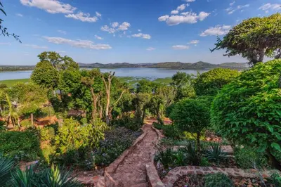 a garden with a view of a lake at Enso Botanico Boutique Villa, Kosmos in Hartbeespoort
