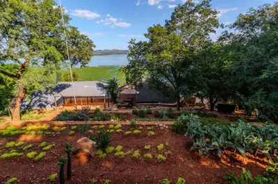 a garden with a view of a lake at Enso Botanico Boutique Villa, Kosmos in Hartbeespoort