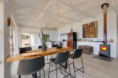 a kitchen and living room with a wooden table and chairs at Enso Botanico Boutique Wellness Villa, with an outside wood-fire Hot Tub in Kosmos in Hartbeespoort