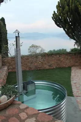 a swimming pool with a fountain in a garden at Enso Botanico Boutique Wellness Villa, with an outside wood-fire Hot Tub in Kosmos in Hartbeespoort