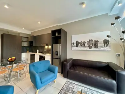 a living room with a leather couch and a blue chair at Deluxe fully furnished apartment in Menlyn Maine residence 1209 in Pretoria