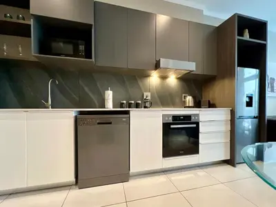a kitchen with white cabinets and a dishwasher at Deluxe fully furnished apartment in Menlyn Maine residence 1209 in Pretoria