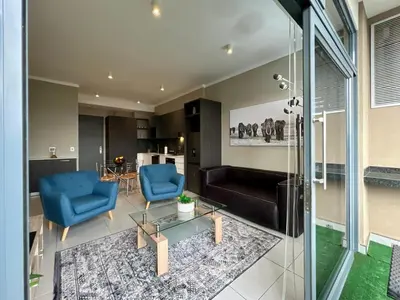 a living room with two blue chairs and a table at Deluxe fully furnished apartment in Menlyn Maine residence 1209 in Pretoria