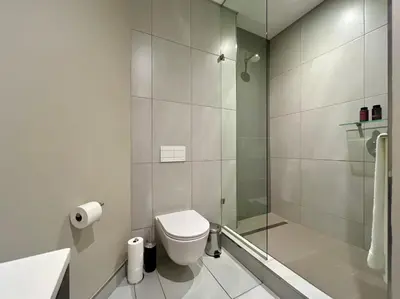 a white bathroom with a toilet and a shower at Deluxe fully furnished apartment in Menlyn Maine residence 1209 in Pretoria