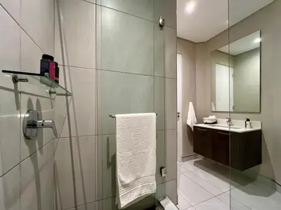 a bathroom with a shower with a sink and a mirror at Deluxe fully furnished apartment in Menlyn Maine residence 1209 in Pretoria