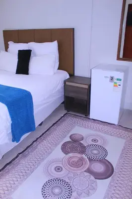 a bedroom with a bed and a rug on the floor at Fargon Guest House in Polokwane