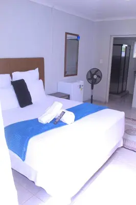 a bedroom with two white beds and a fan at Fargon Guest House in Polokwane