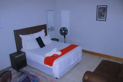 a bedroom with a white bed with a red blanket at Fargon Guest House in Polokwane