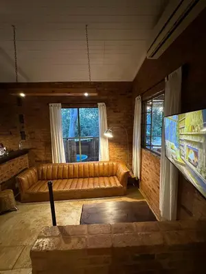 a living room with a couch and a television at Wild Fig Cottage with Tickle Tub in Hartbeespoort in Pelindaba