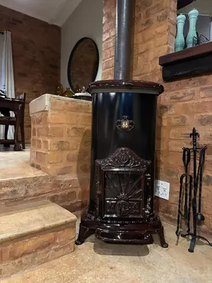 a black stove sitting in a room with stairs at Wild Fig Cottage with Tickle Tub in Hartbeespoort in Pelindaba