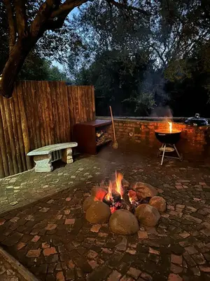 a fire pit with a grill and a bench at Wild Fig Cottage with Tickle Tub in Hartbeespoort in Pelindaba