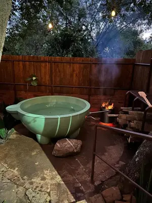 a green bath tub sitting next to a fire at Wild Fig Cottage with Tickle Tub in Hartbeespoort in Pelindaba