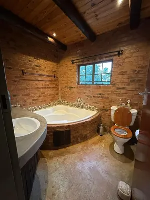a bathroom with a tub and a toilet and a sink at Wild Fig Cottage with Tickle Tub in Hartbeespoort in Pelindaba