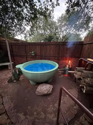 a bath tub sitting in a yard next to a fire at Wild Fig Cottage with Tickle Tub in Hartbeespoort in Pelindaba