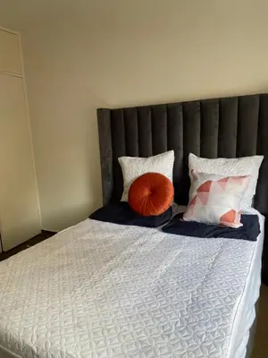 a large bed with a gray headboard and pillows at Kim in Pretoria