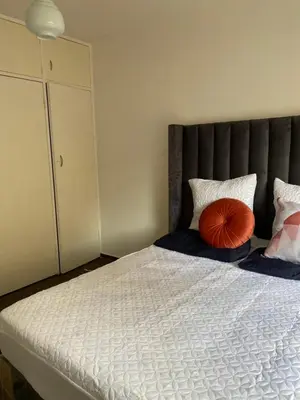 a bedroom with a large bed with a red pillow at Kim in Pretoria